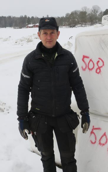Bild på Nils Söderberg, Helleby Gård, framför balar.