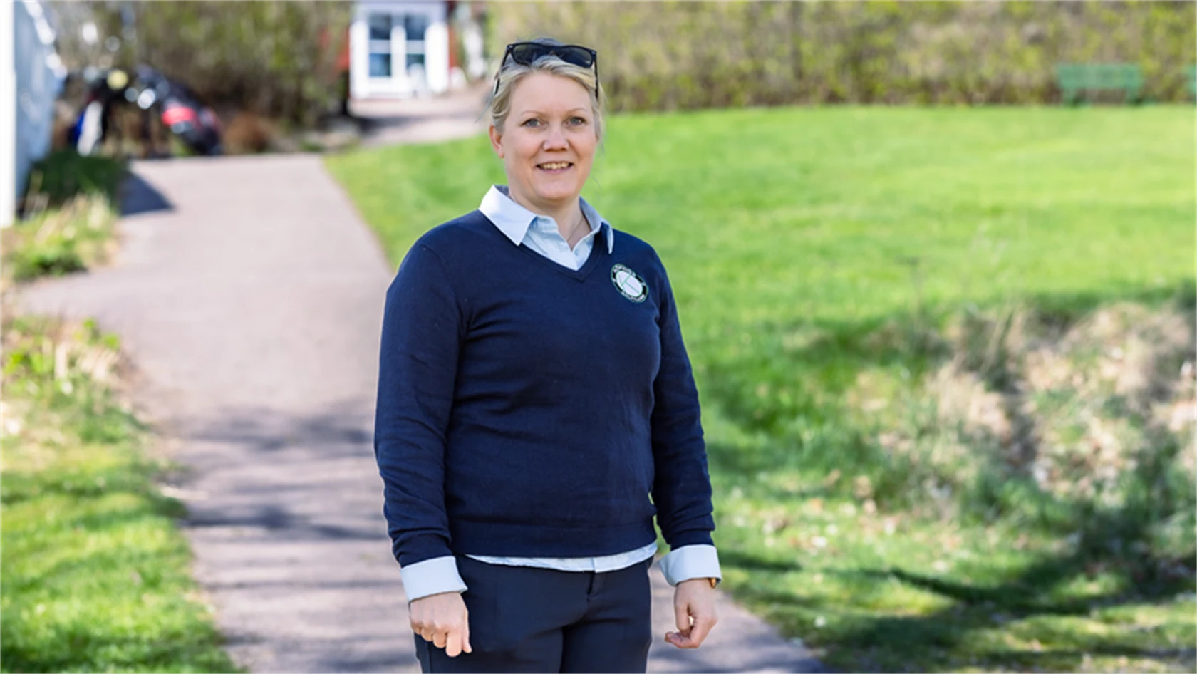 Bild på Lena Björkdahl som är klubbchef för Köpings Golfklubb. Hon står utomhus utanför golfklubben.