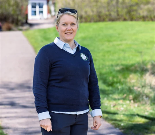 Bild på Lena Björkdahl som är klubbchef för Köpings Golfklubb. Hon står utomhus utanför golfklubben.