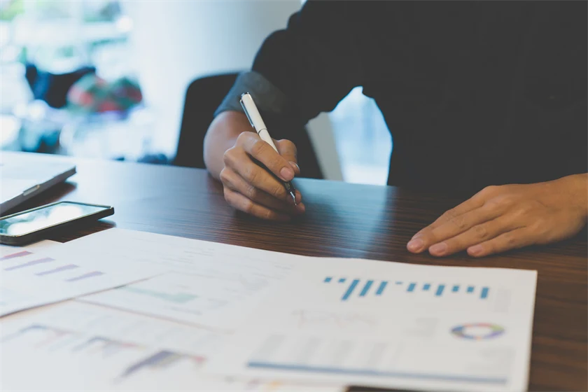 Bild på person med utskrivna papper framför sig med olika typer av grafer och diagram.