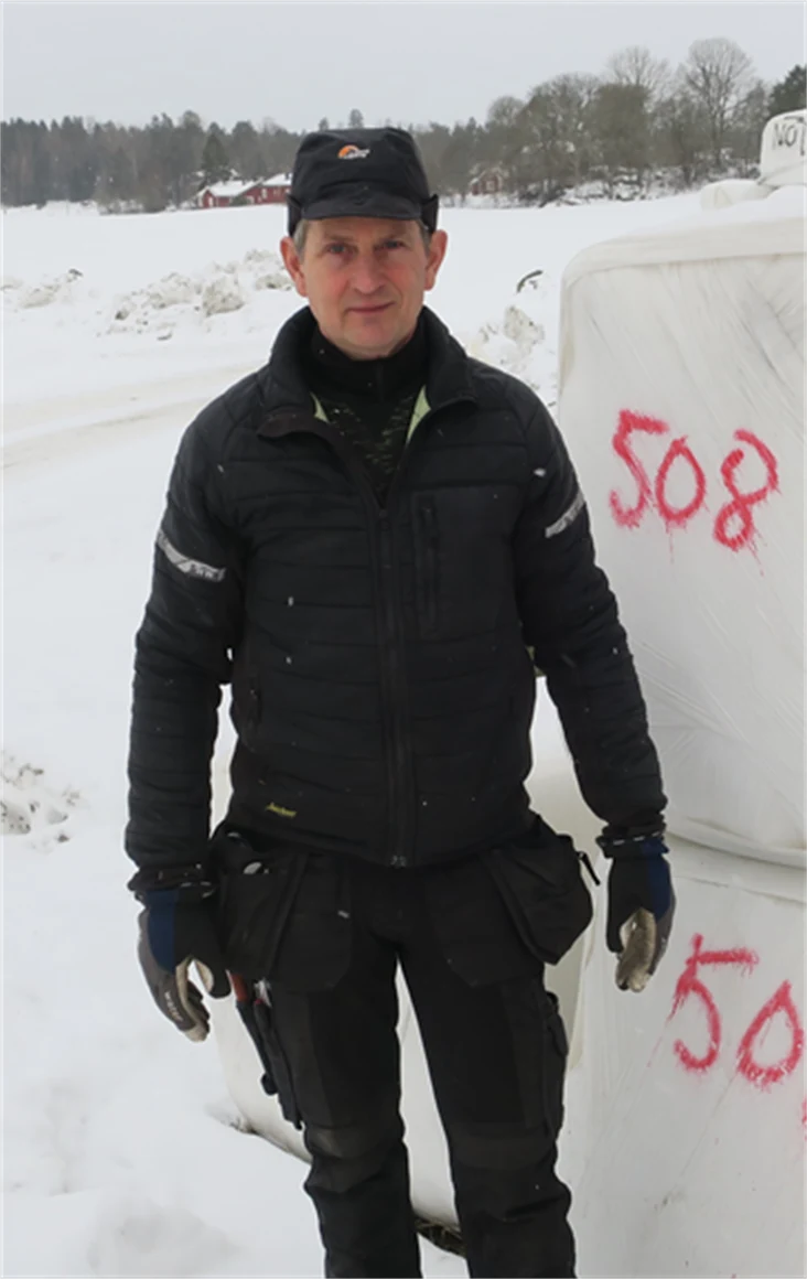 Bild på Nils Söderberg, Helleby Gård, framför balar.