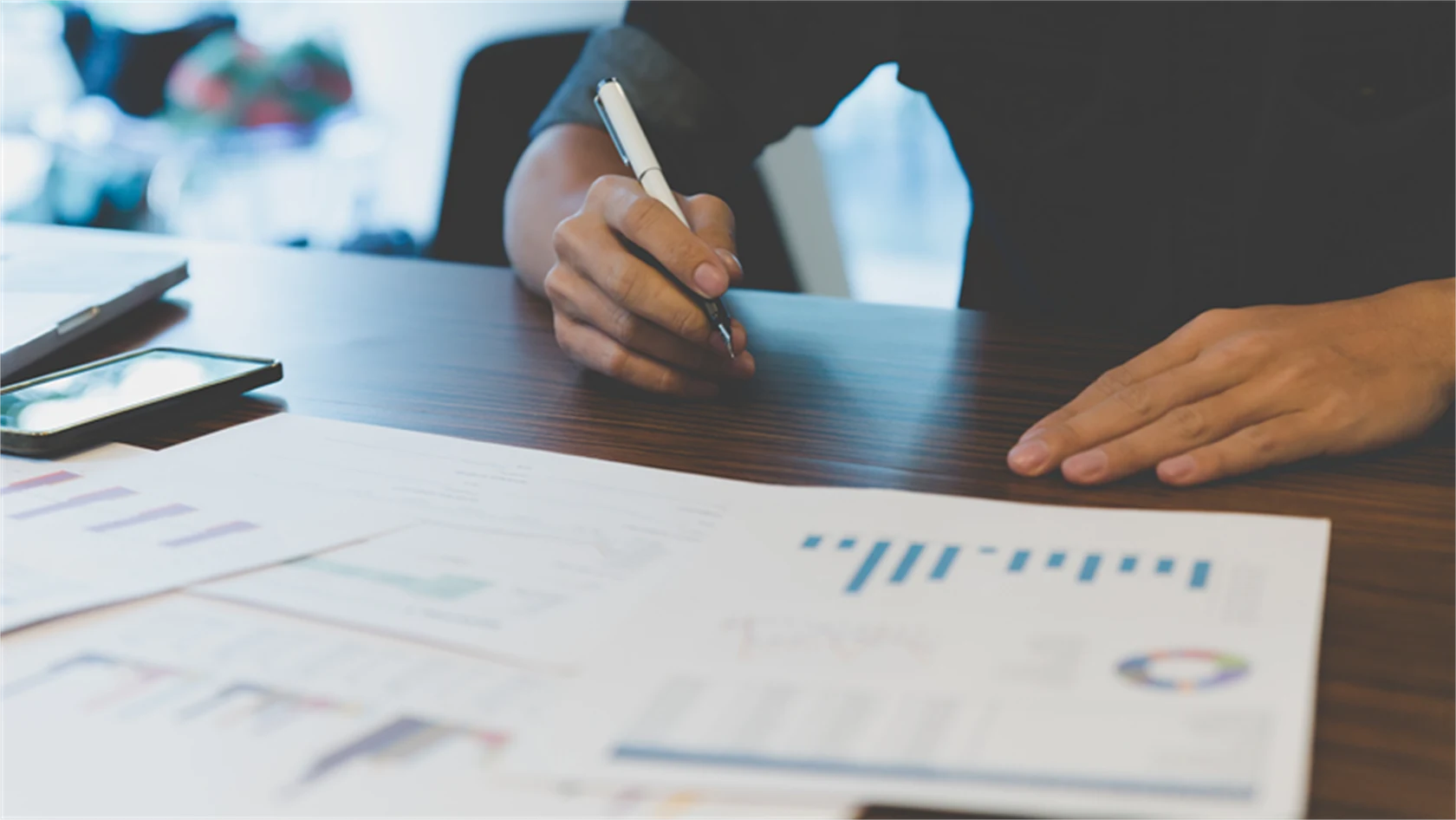 Bild på person med utskrivna papper framför sig med olika typer av grafer och diagram.