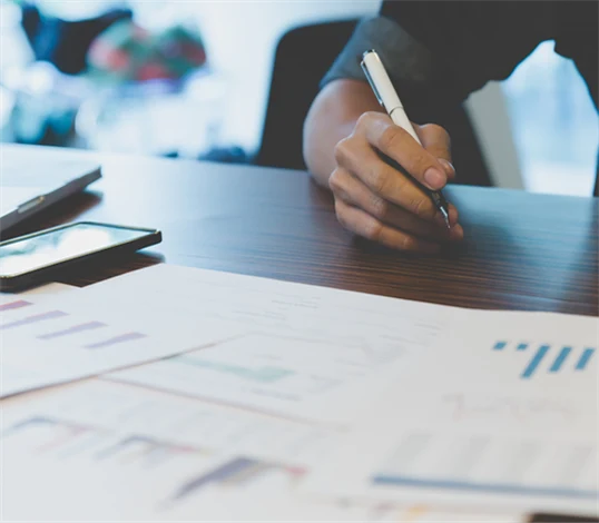 Bild på person med utskrivna papper framför sig med olika typer av grafer och diagram.