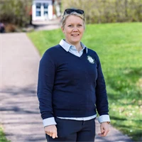 Bild på Lena Björkdahl som är klubbchef för Köpings Golfklubb. Hon står utomhus utanför golfklubben.